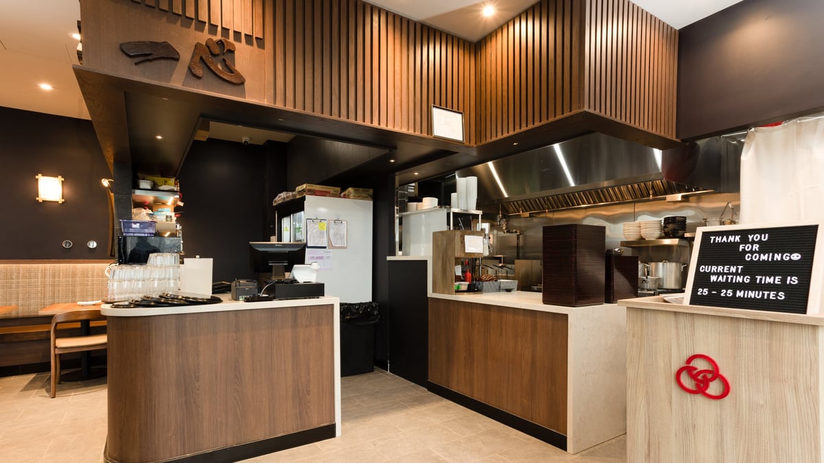 Modern cafe interior with wooden and black counter, espresso machine, and menu board in warm lighting